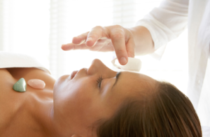 Therapist placing quartz crystal on woman's forehead